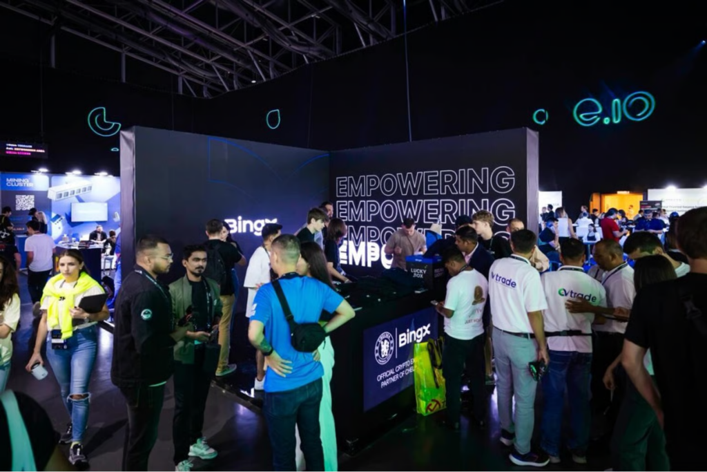 Crowded blockchain expo booth with BingX branding and 'Empowering' text on dark backdrop.