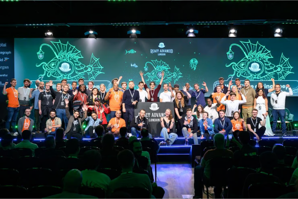 Conference speakers, organizers, and attendees on the stage of React Advanced stage