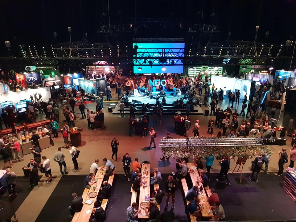 NDC Oslo attendees networking and exploring exhibits in a large conference hall
