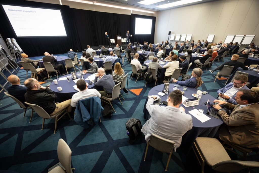 Conference attendees seated at round tables watching a presentation session on stage at RSAC