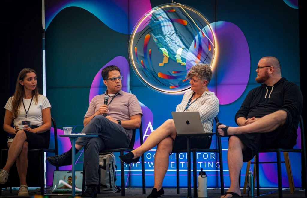 Four panelists seated on stage discuss software and technology topics during a session at CAST Conference
